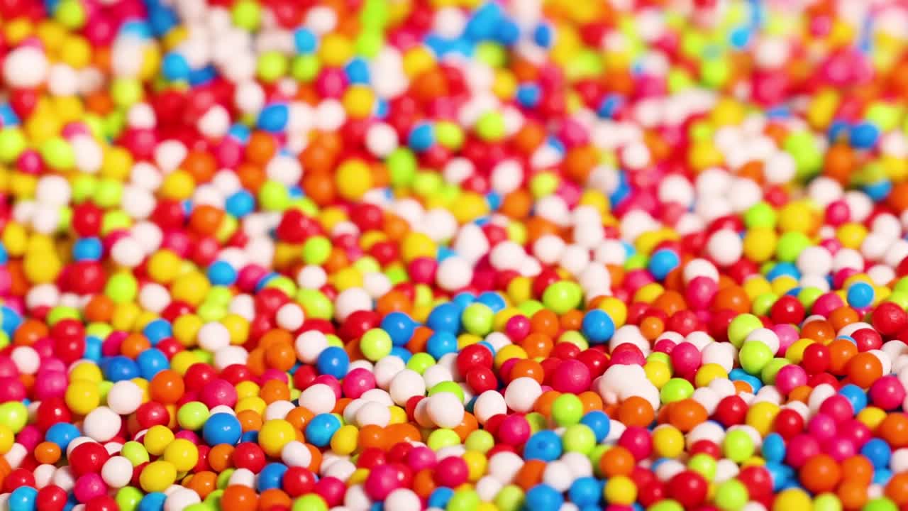 Close-up view of fingers interacting with a vibrant mix of small, colorful candy sprinkles.