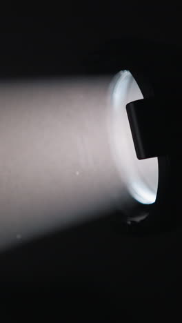 un haz de luz enfocado de una linterna de mano ilumina una habitación oscura, creando un rayo lineal distinto a través del espacio sombrío