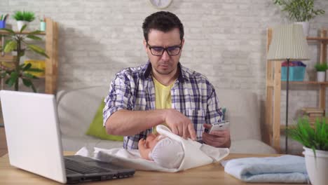 un joven futuro padre aprende a envolver a un niño con un teléfono inteligente en la mano de cerca
