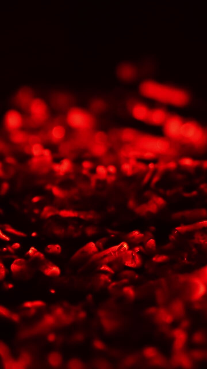Wood in the campfire burnt out and charcoal is still hot. Red charcoal glowing. Close up. Vertical video