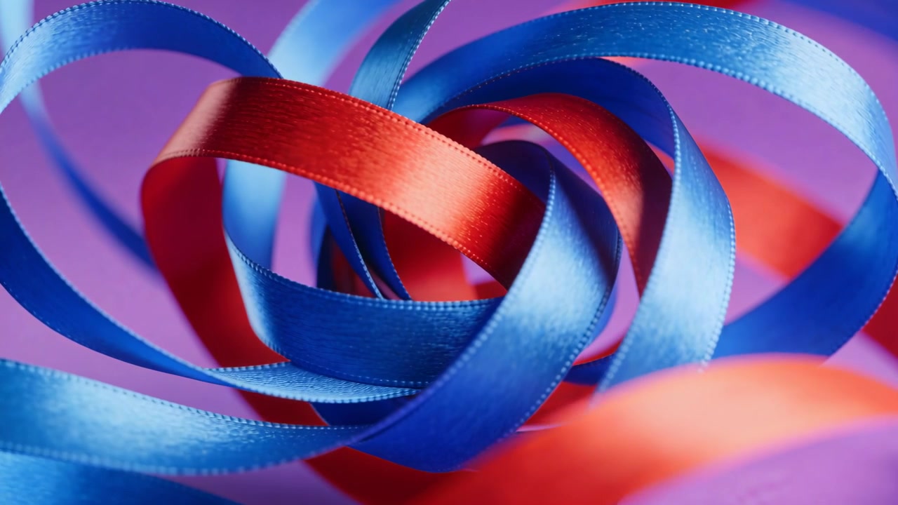 La telecamera riprende nastri di raso rossi e blu che si stringono in un nodo, in un primo piano in studio con bordi cuciti.