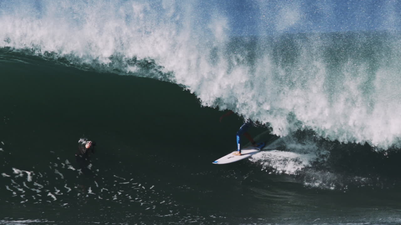 Wave hurls over crouched surfer in clean overhead barrel curling toward camera