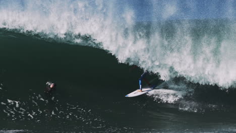 wave hurls over crouched surfer in clean overhead barrel curling toward camera