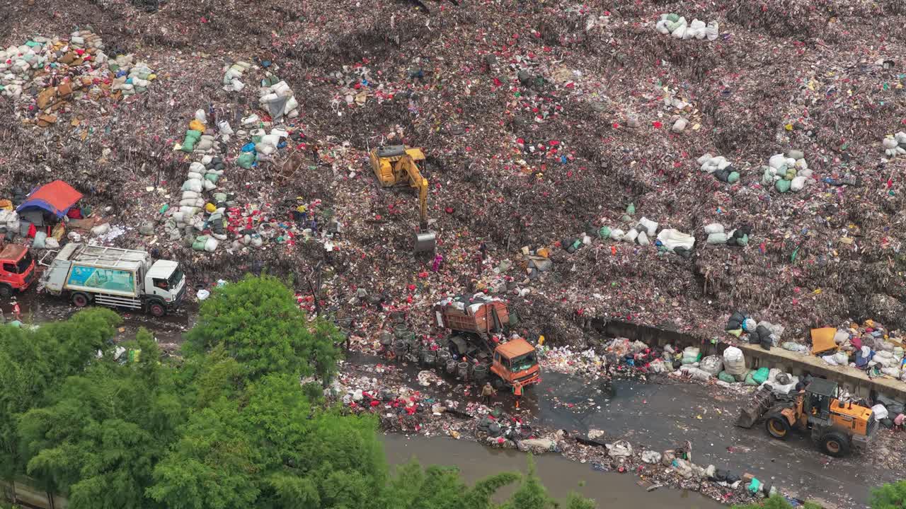 Macchinari pesanti che gestiscono un'enorme discarica di rifiuti a Jakarta