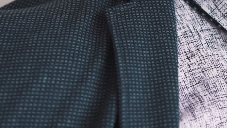 Man-in-patterned-shirt-puts-on-dark-jacket-extreme-closeup