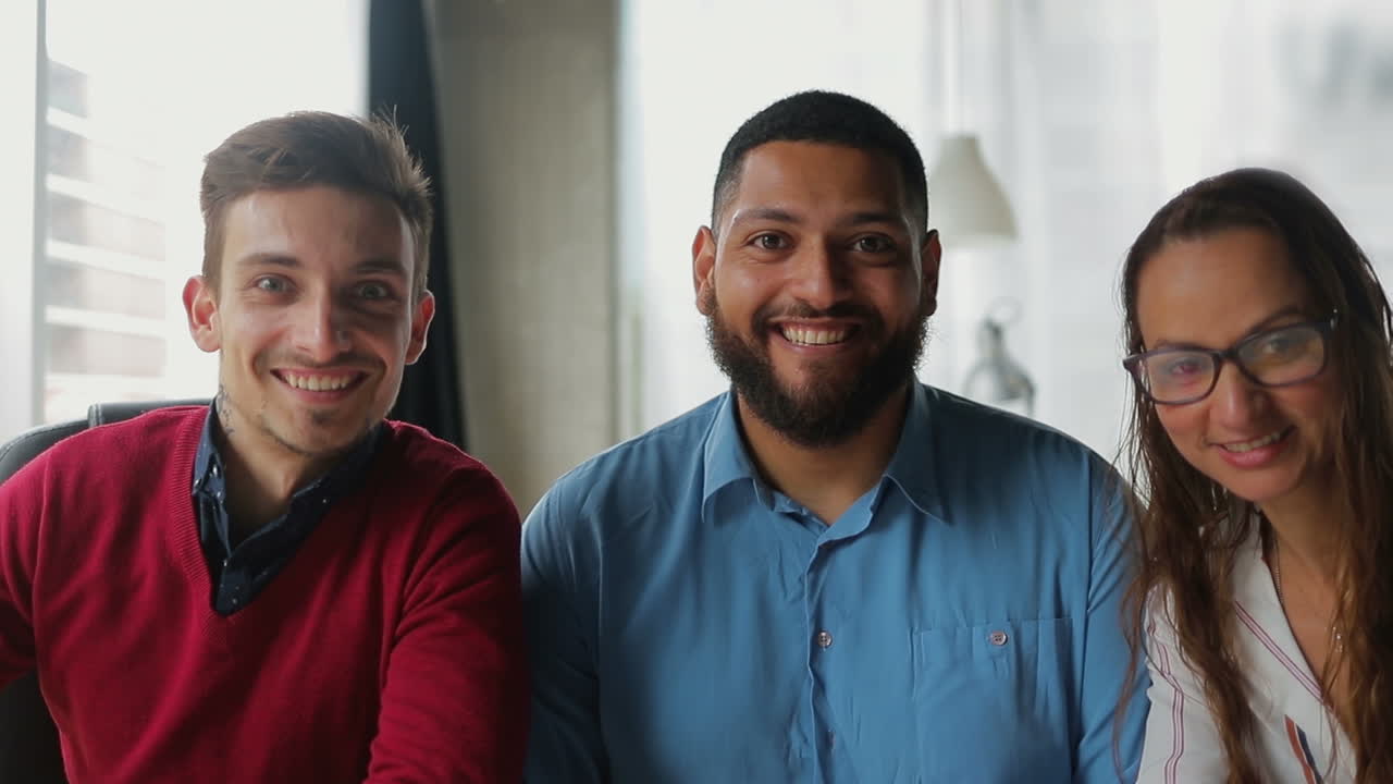 jóvenes sonrientes saludando y mirando a la cámara.