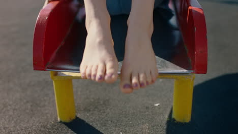 close-up-feet-woman-sliding-on-playground-slide-enjoying-fun-on-summer-vacation-teenage-girl-barefoot-in-school-yard
