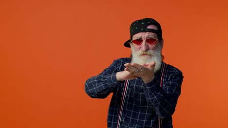 viejo abuelo barbudo maduro con gafas de sol que muestra desperdiciando o arrojando dinero alrededor del gesto de la mano