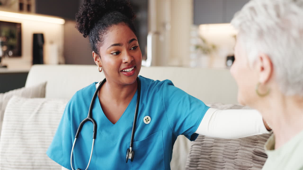Young Nurse Comforting and Talking with Senior Woman During Home Visit