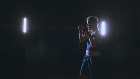 A-strong-athletic,-woman-boxer,-boxing-at-training-on-the-black-background.-Sport-boxing-Concept-with-copy-space.