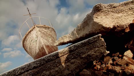 low-angle-shot-of-old-boat-ruin-left-out-of-sea-sky-with-clouds-cinematic-establishment-shot-,-abandoned-wooden-ancient-ship