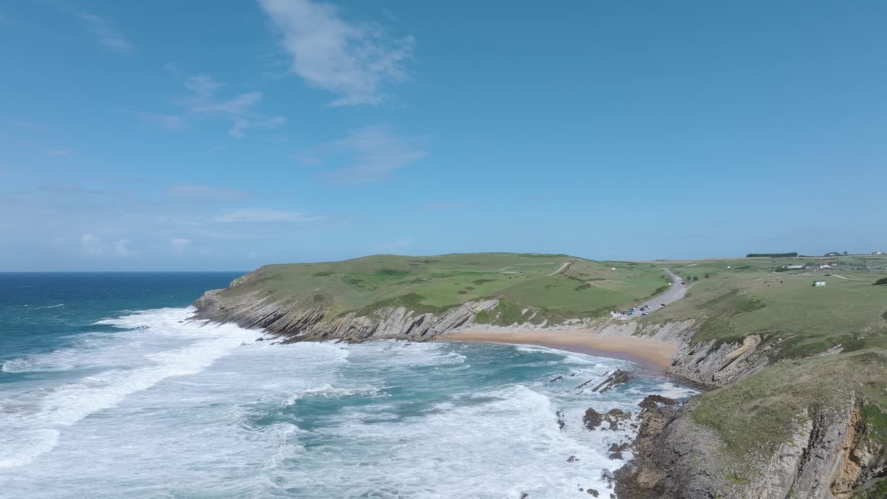Slow-motion drone flight along the Cantabrian coast at sunset, showcasing the powerful sea, the stunning Tagle beach, and the dramatic cliffs where the ruined 14th-century tower of San Telmo stands