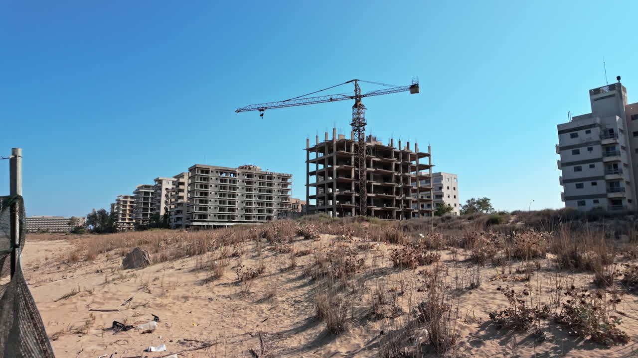 Abandoned buildings with construction crane in Varosha under clear blue sky