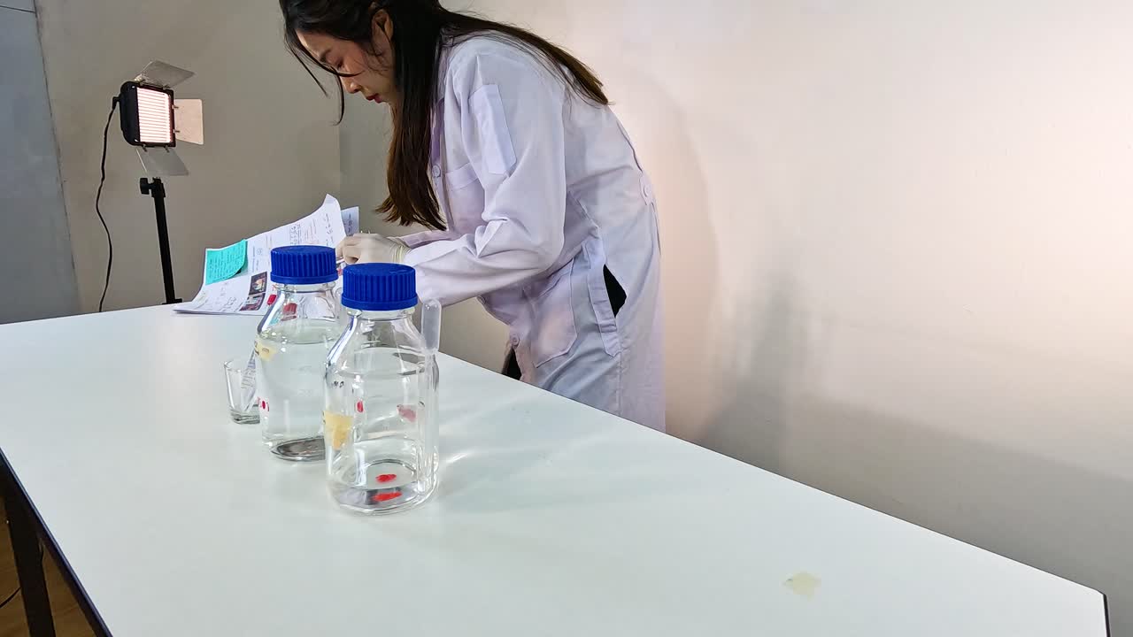 A scientist in a lab coat prepares a chemical experiment, referencing a manual. Bright lighting highlights the laboratory setting