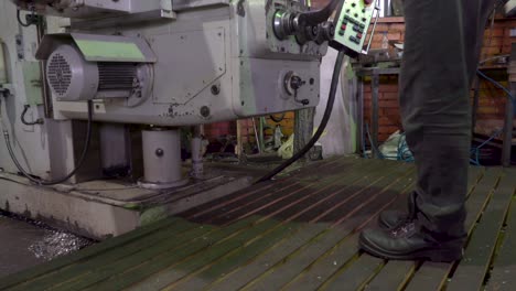 Worker operating a drilling machine in a factory.