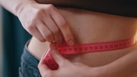 closeup hands measuring waist stomach holding tape. perfect fitness motivation