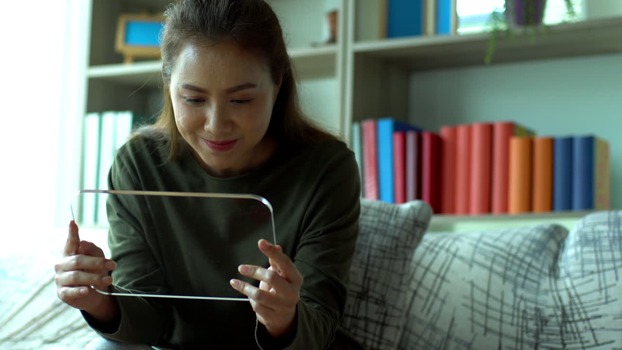 una simulación virtual futurista de una hermosa mujer asiática que disfruta jugando con una tableta avanzada simulada mirando un informe infográfico del mercado de valores en casa