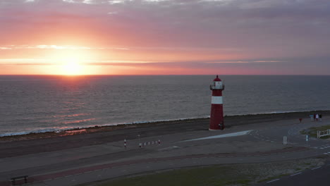 el faro de westkapelle durante una puesta de sol naranja brillante, con mucho viento