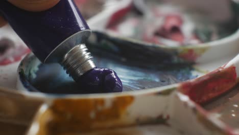 Squeezing-paint-from-tube-on-artist-painting-palette,-close-up