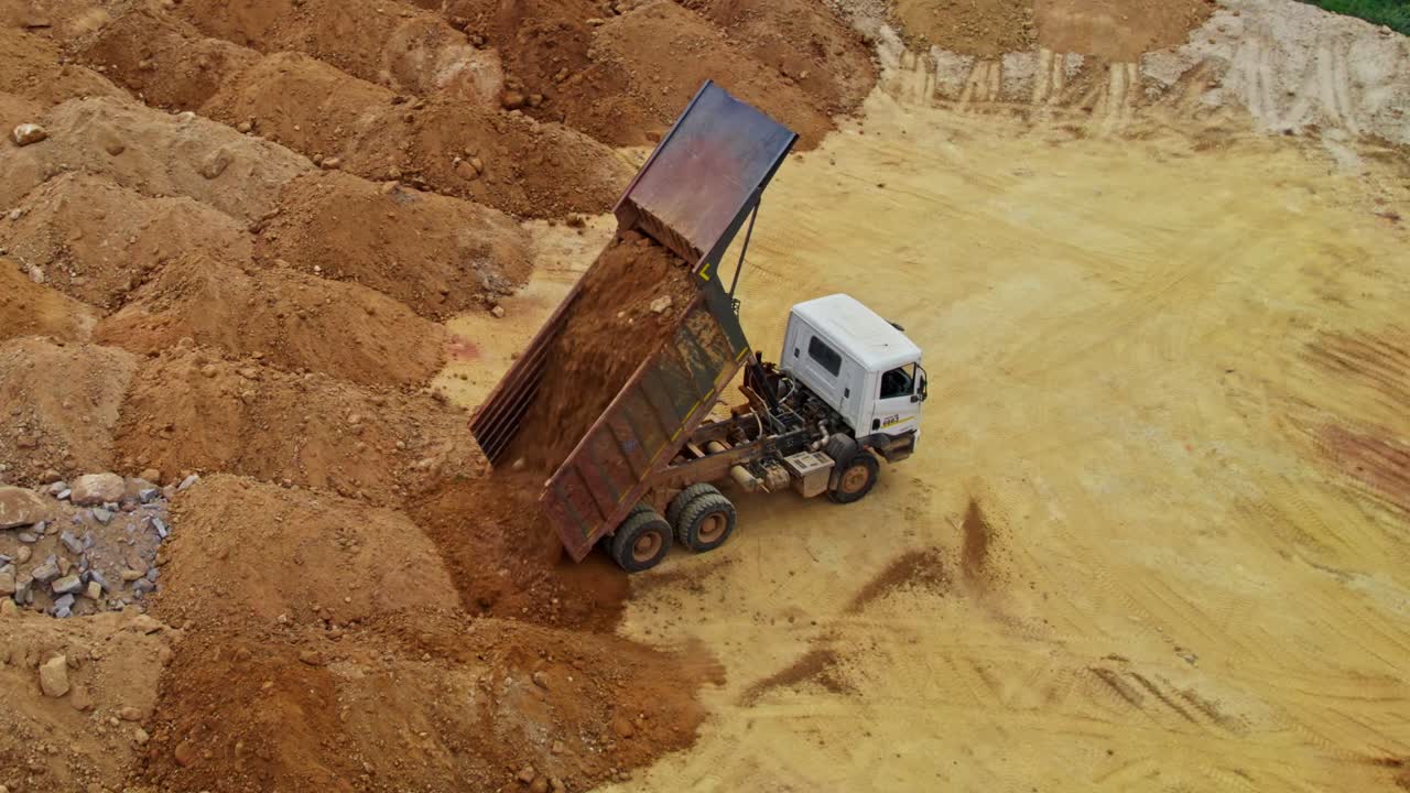 Truck unloading sand and dumping in construction area at telangana, india. day time, semi circle, drone shot. 4k