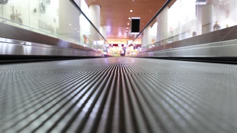 Moving-walkway-at-the-airport,-also-known-as-an-autowalk,-moving-sidewalk,-moving-pavement,-people-mover,-travolator,-or-travelator,-is-a-slow-moving-conveyor-mechanism-that-transports-people.