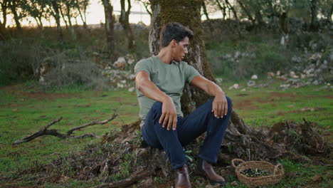 Tired-farmer-resting-olive-tree-nature.-Weary-gardener-man-taking-break-vertical