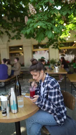 woman using phone at an outdoor cafe