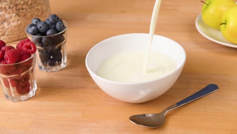 shot of milk being poured down into a bowl to make cereal as breakfast