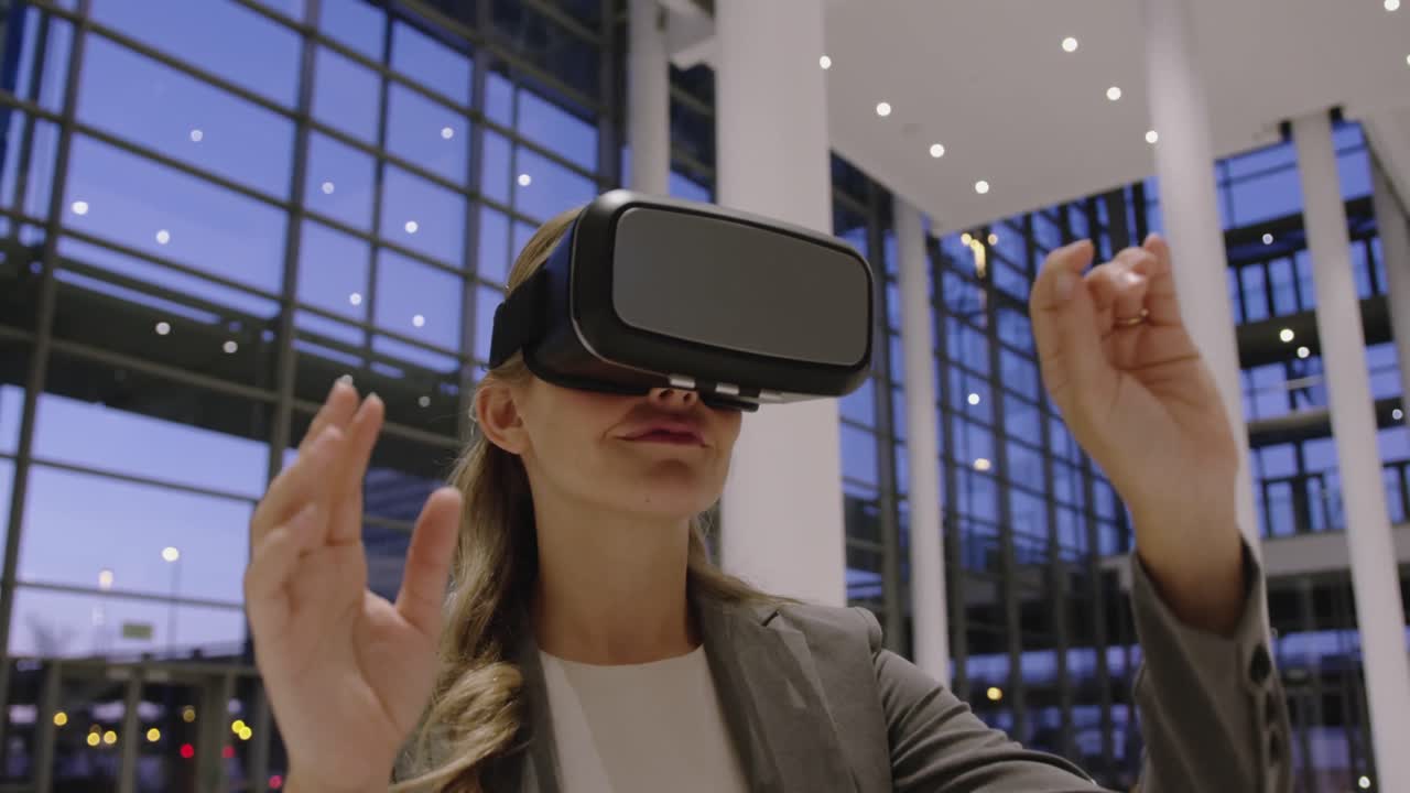 Donna d'affari che usa un visore per la realtà virtuale nella hall dell'ufficio 4k