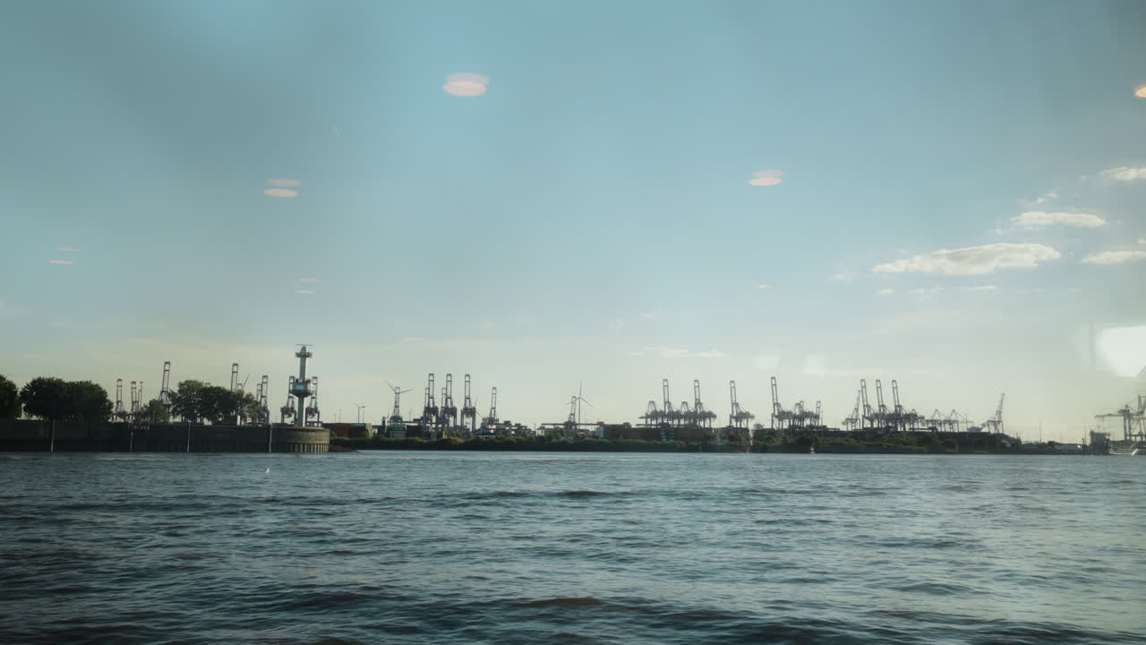 Panoramic view of Hamburg harbor with cranes and water. Ideal for travel documentaries or industrial projects