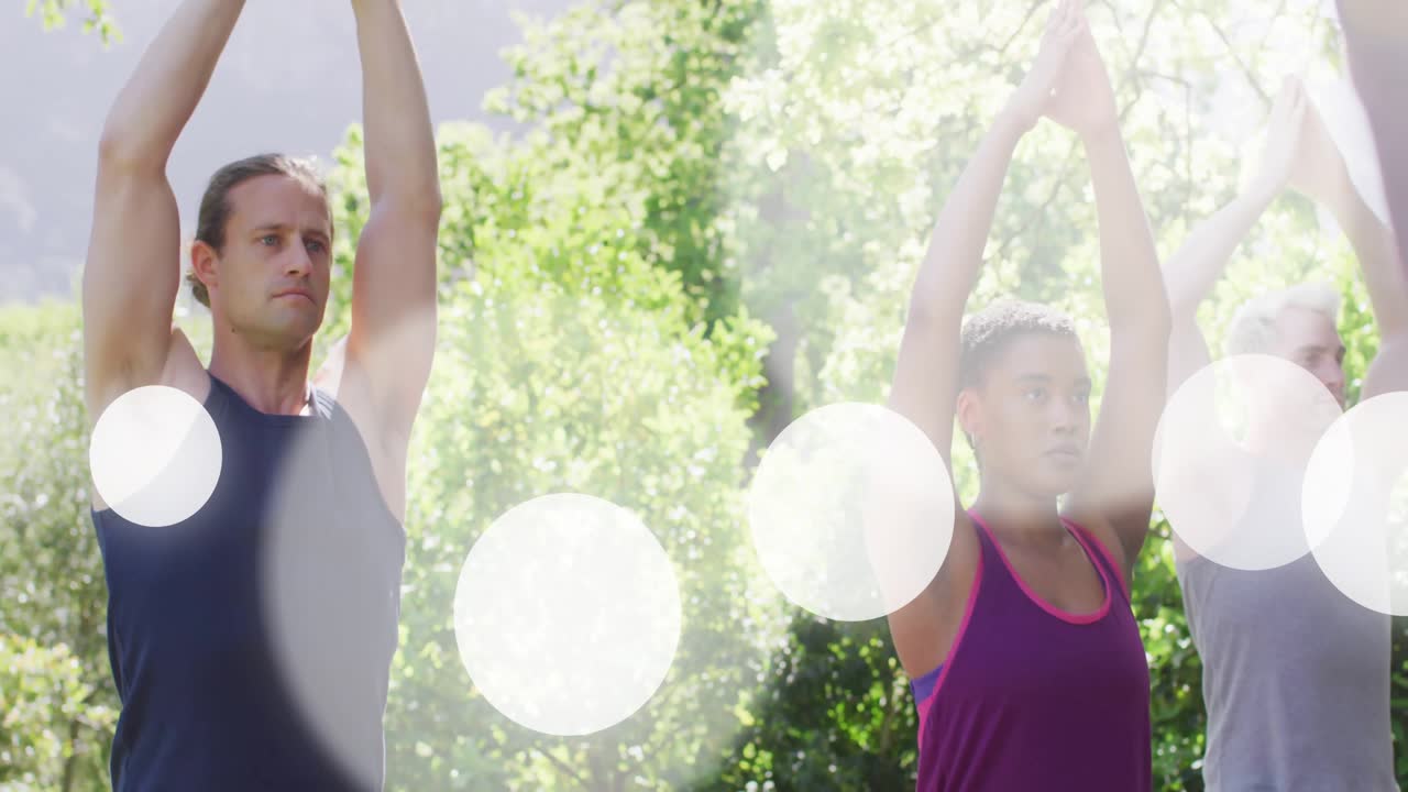 Istruttore che guida un gruppo in una posa yoga di preghiera sopra la testa per il benessere con bagliori di luce che si diffondono.