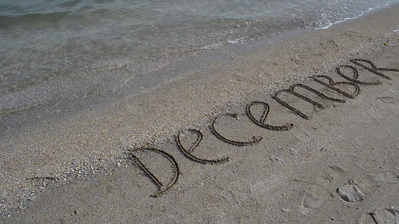 Inscription December on the beach. Shooting on the beach