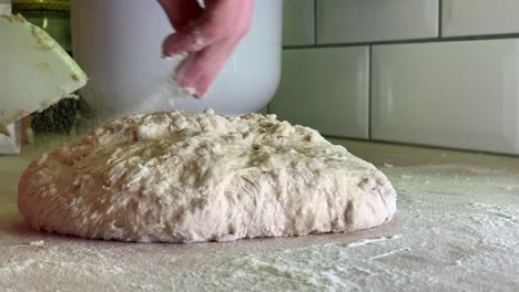 throwing and sprinkling flour over dough on table in slowmotion