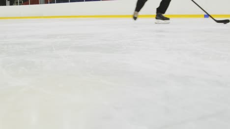 Jugadores-De-Hockey-Entrenando-En-La-Pista-De-Hielo-Con-Palos-Y-Discos-De-Hockey,-Tiro-En-ángulo-Bajo-De-Patines-De-Hockey