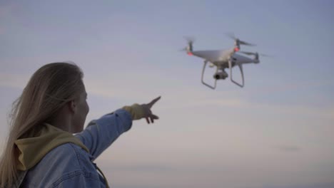 young woman looking at flying above sea quadcopter