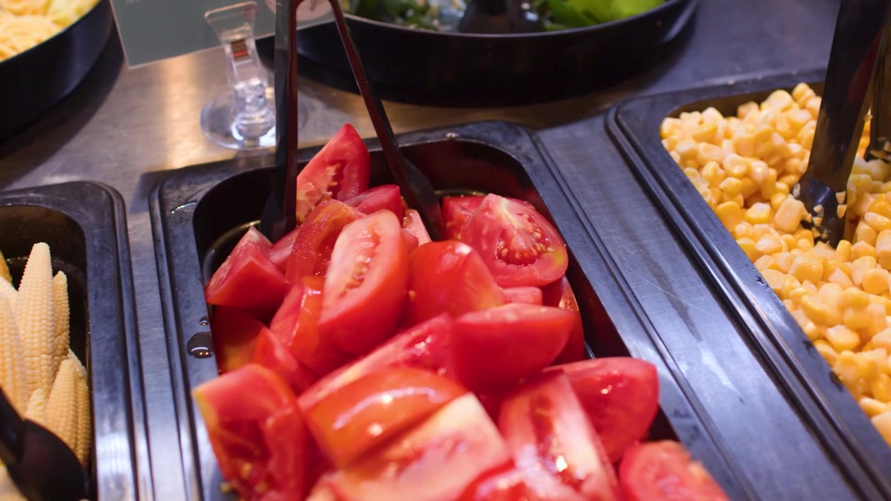 Carrellata ravvicinata di varie verdure fresche e cereali in un salad bar di un ristorante.