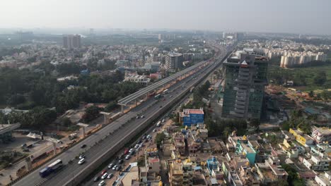 dramatic aerial footage shows residential and commercial buildings on an expanding indian highway, along with a service road and rapidly moving cars