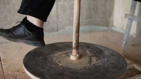 Spinning-pottery-wheel-close-up.-Foot-of-potter-working-in-pottery-workshop.-Beautiful-young-woman-working-on-vase-in-pottery-master-class