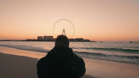 Mann-Fotografiert-Seelandschaft-Mit-Riesenrad-Bei-Sonnenuntergang