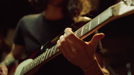 Unrecognizable-person-rehearsing-with-acoustic-guitar-in-recording-studio.