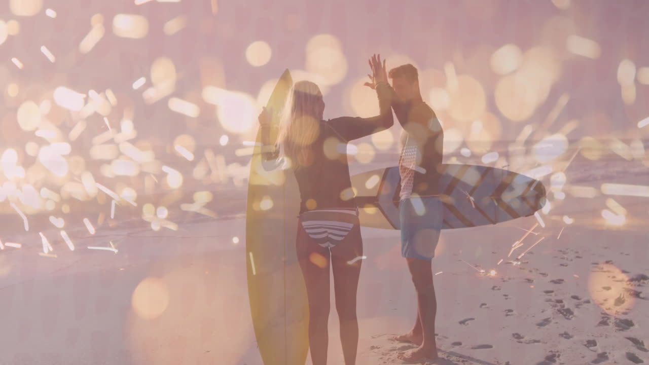 Surfers on beach with boards, enjoying animation of sparkling light effects