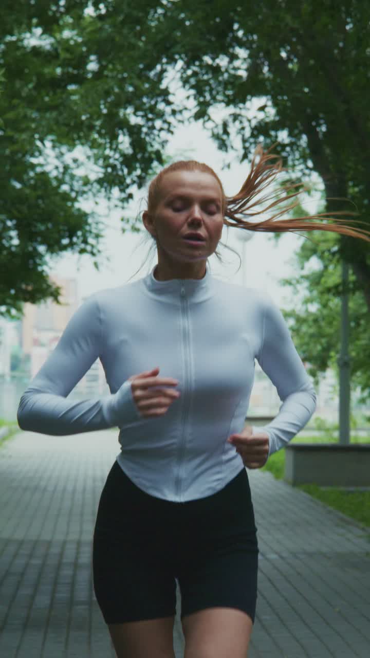 A Focused Runner Enjoys a Refreshing Morning Jog Along a Scenic Path Surrounded by Lush Greenery and Urban Landscape