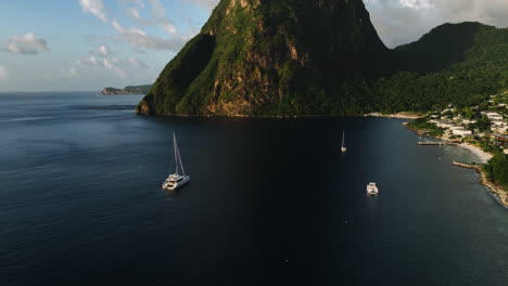 gros piton mountain and the jalousie town, sunset in st lucia - aerial tilt reveal