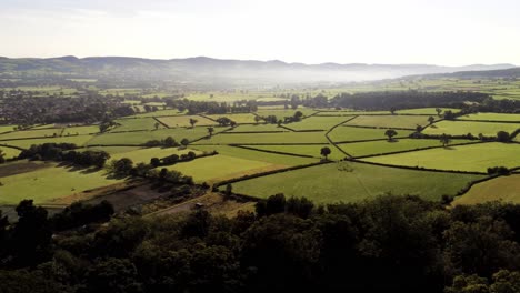 Beautiful-British-misty-farmland-patchwork-countryside-rural-landscape-aerial-right-panning-view