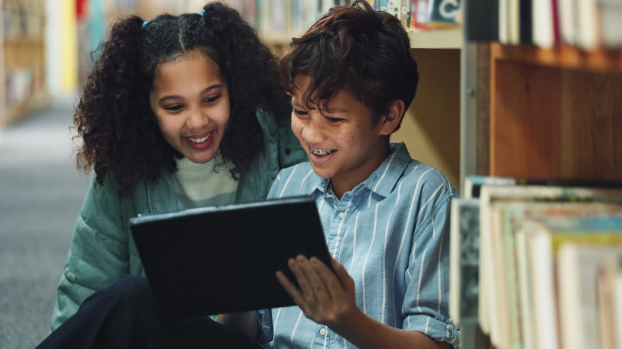 Two children reading a tablet in a library