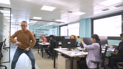 cheerful businessman dancing while colleagues cheering for him in creative workspace