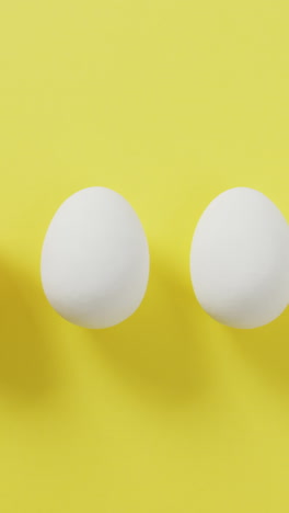 video of row of one brown and four white eggs with copy space on yellow background