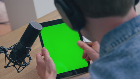 close up of male vlogger live streaming looking at green screen digital tablet