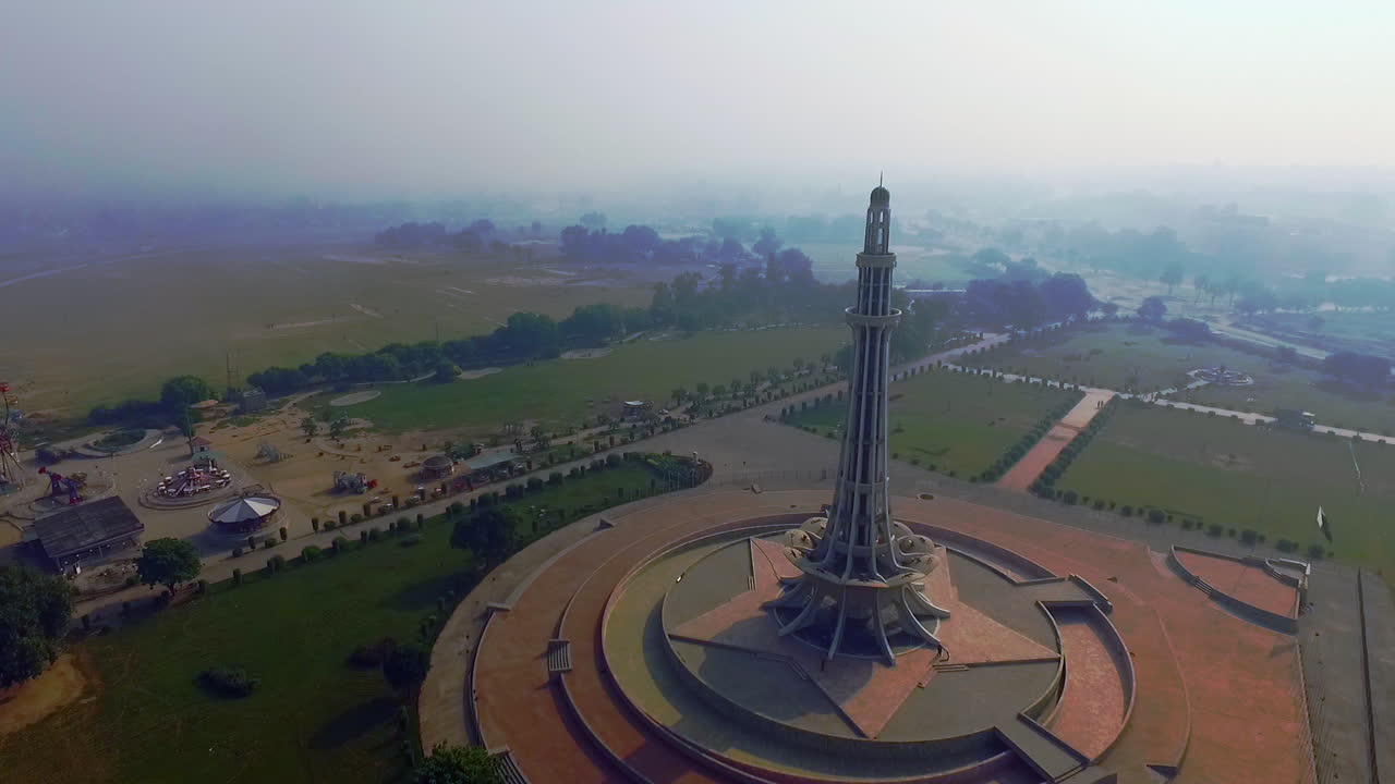Luftfoto af Minar-e-Pakistan med sin forlystelsespark, mod solen, et nationalt monument beliggende i Lahore, Pakistan
