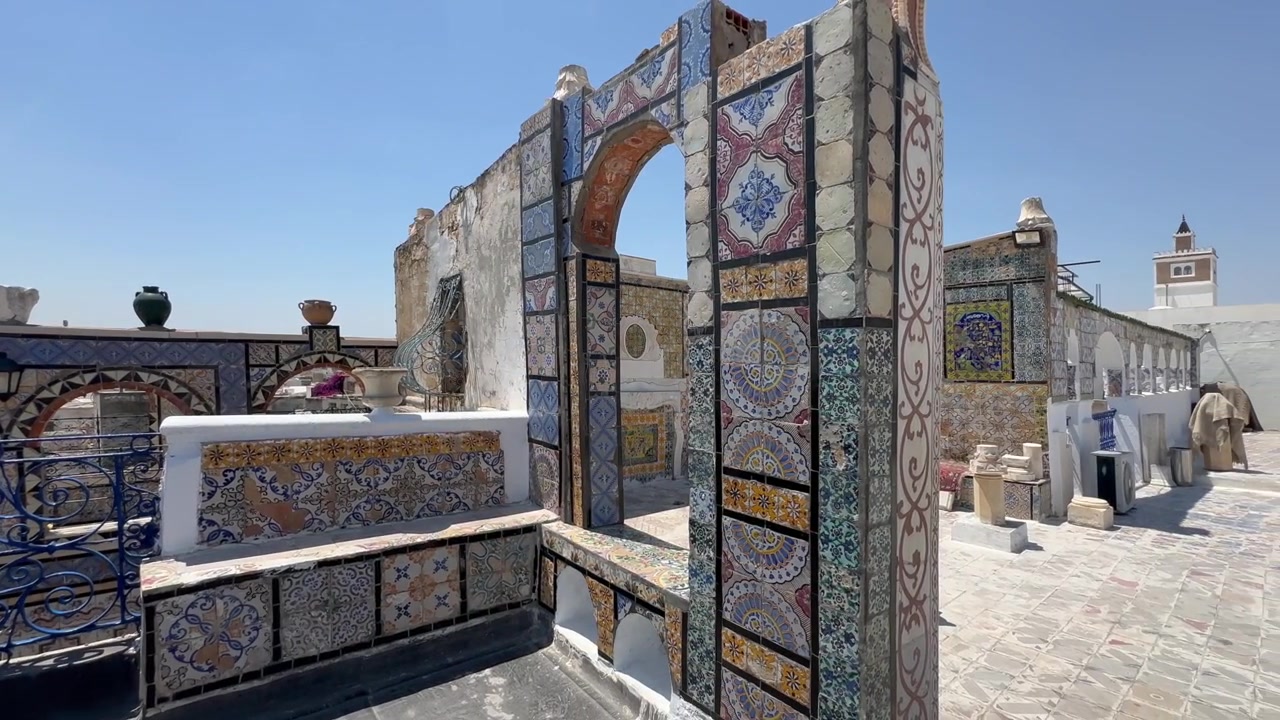 Intricati lavori in piastrelle coprono un arco sul tetto e panchine a Tunisi, Tunisia.